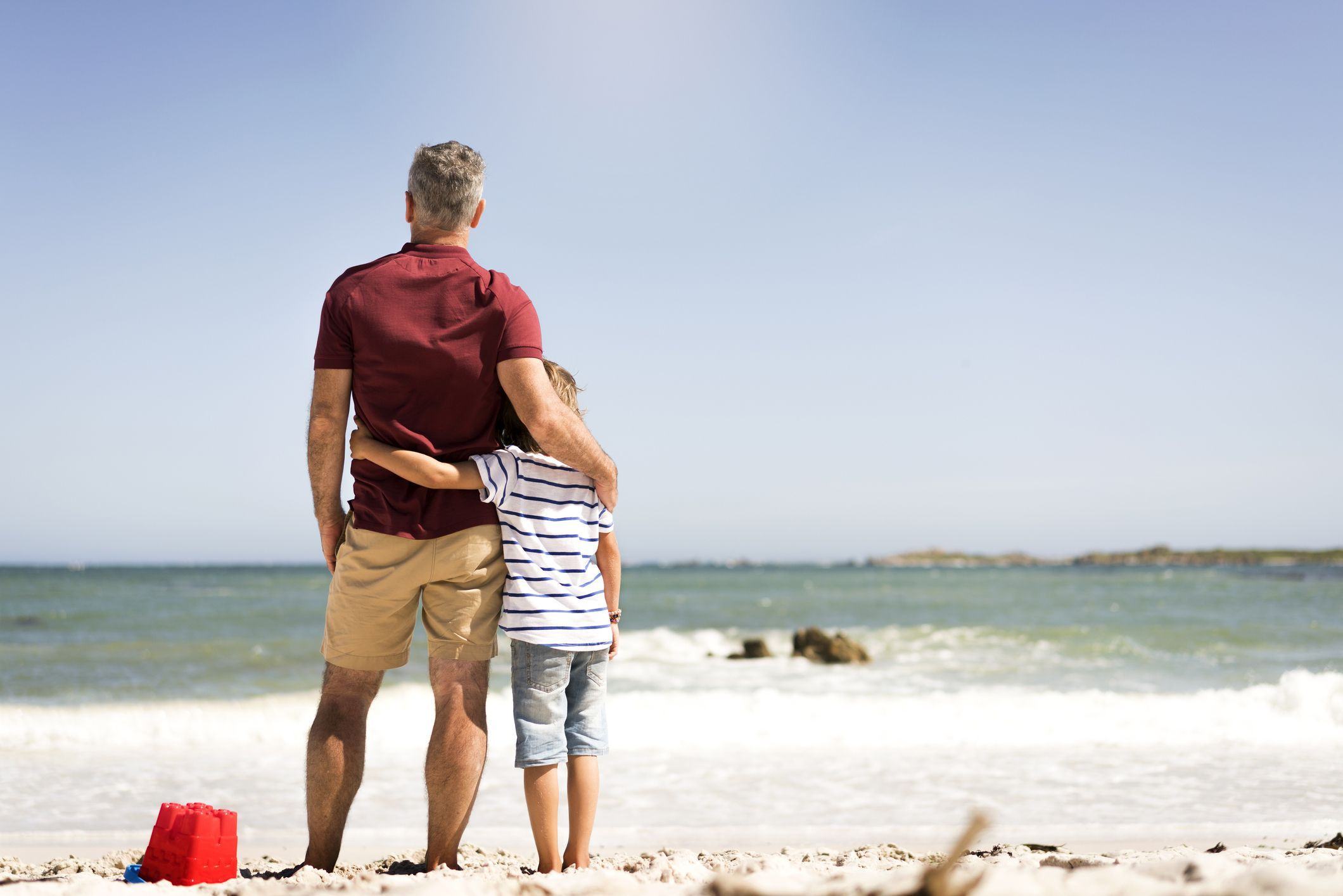 Hình ảnh hai cha con đứng bên nhau trên bãi biển cát trắng