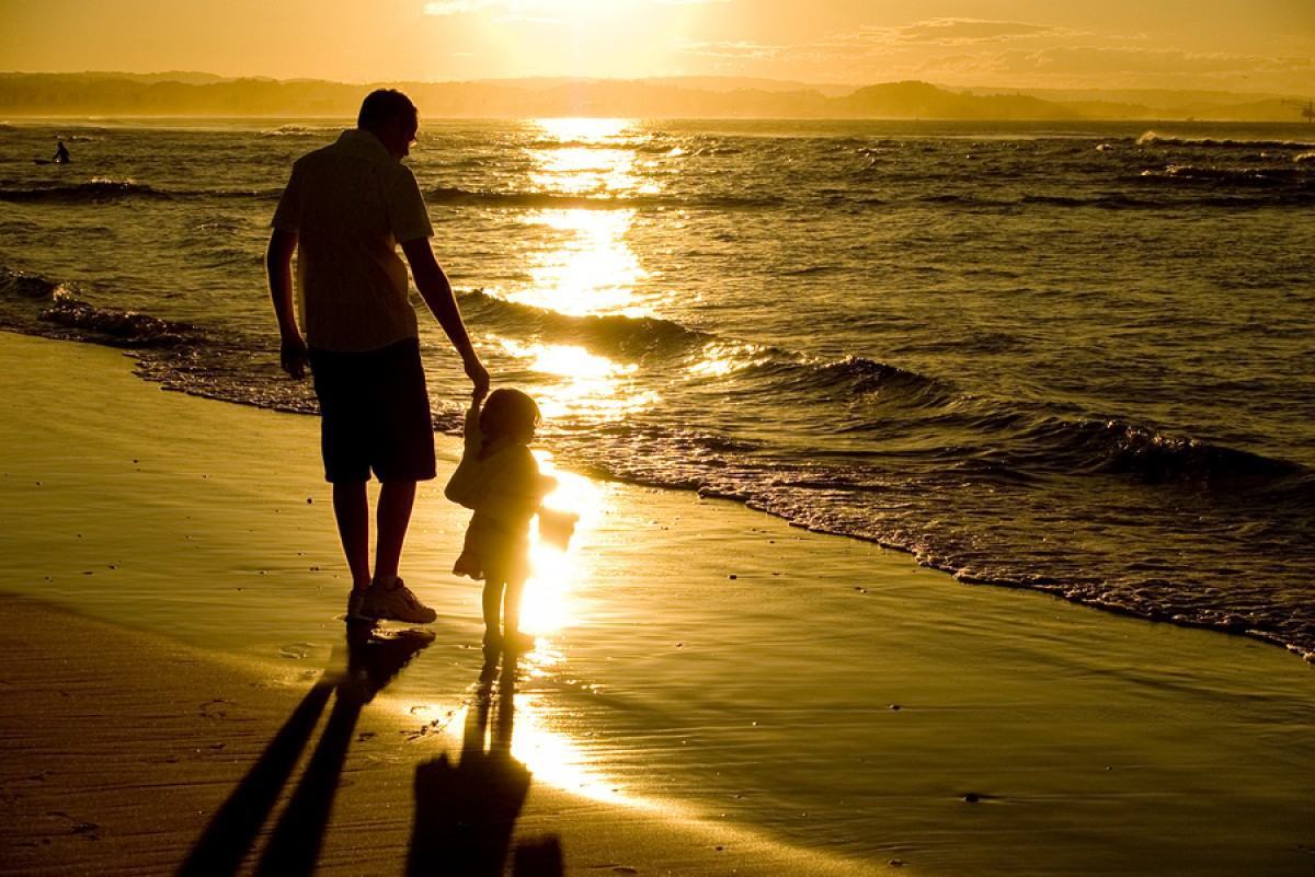 Hình ảnh hai cha con nắm tay nhau đi dạo trên bãi biển