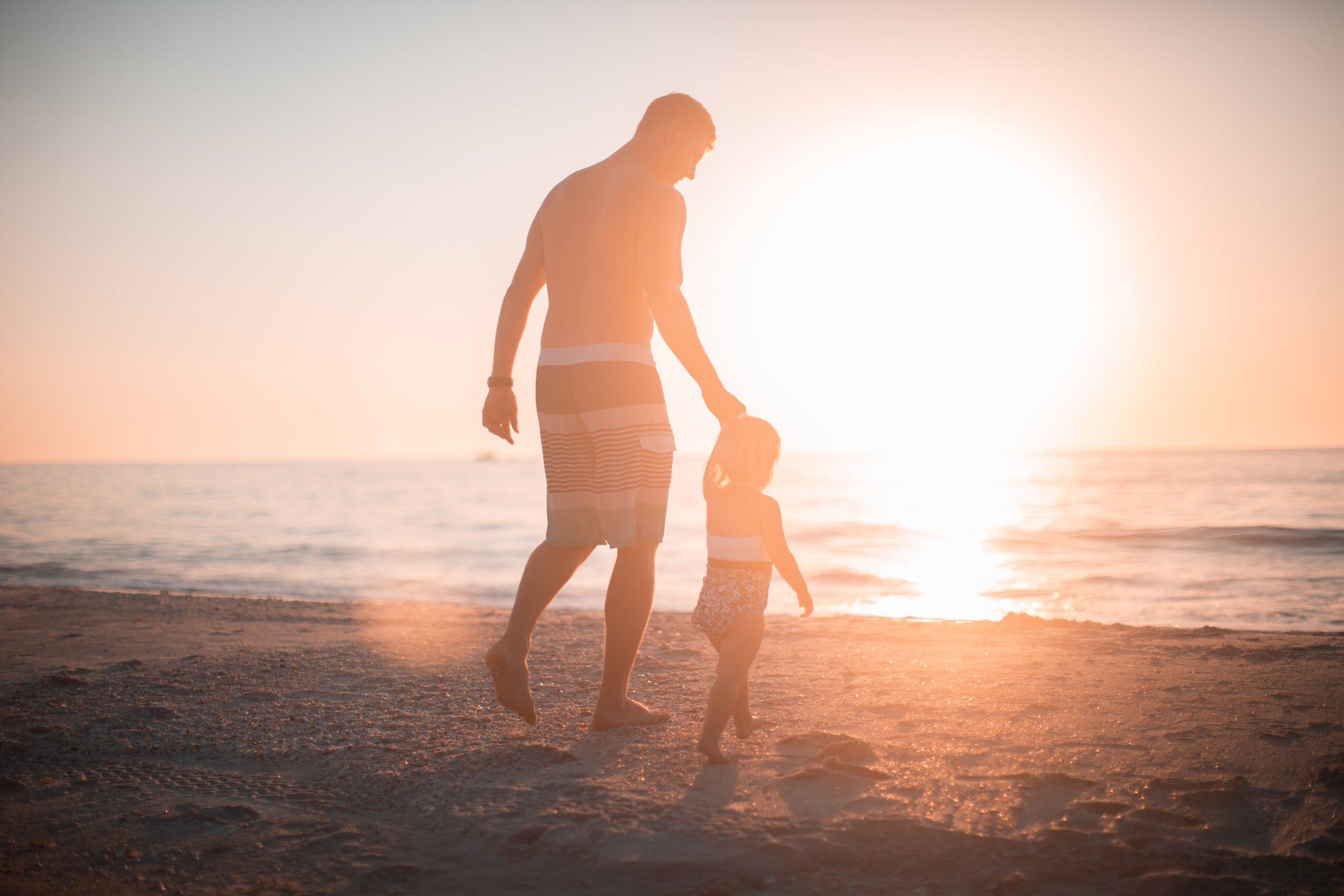 Hình ảnh cha và con gái đi dạo trên bãi biển đầy nắng
