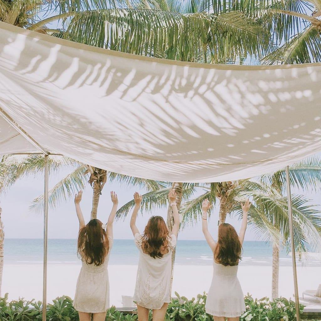 Hình ảnh ba cô gái tựa bãi biển dưới gốc dừa