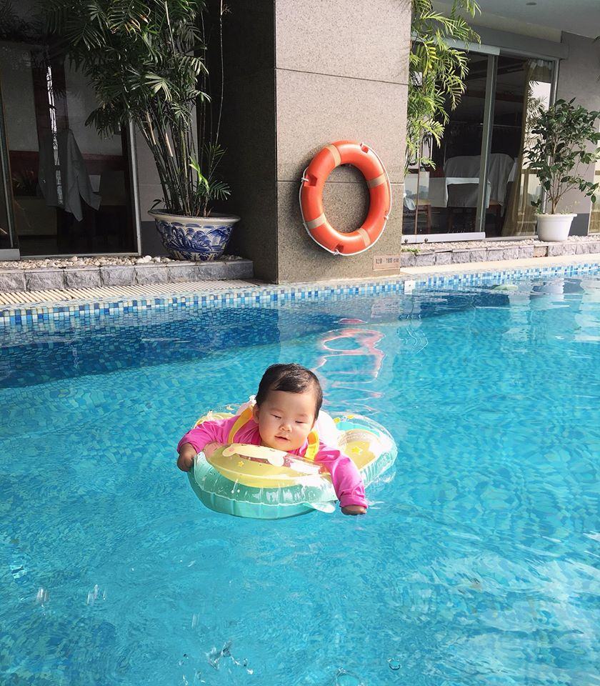Hình ảnh em bé dễ thương nằm trên phao bơi