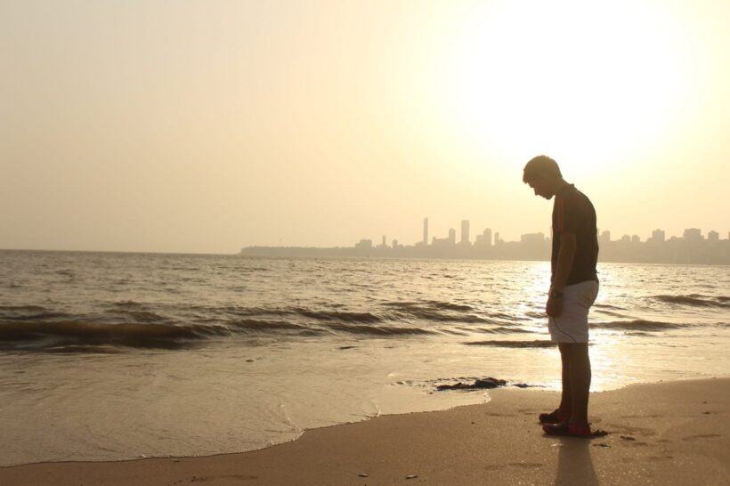 Hình ảnh chàng trai đau lòng đứng trên bãi biển một mình